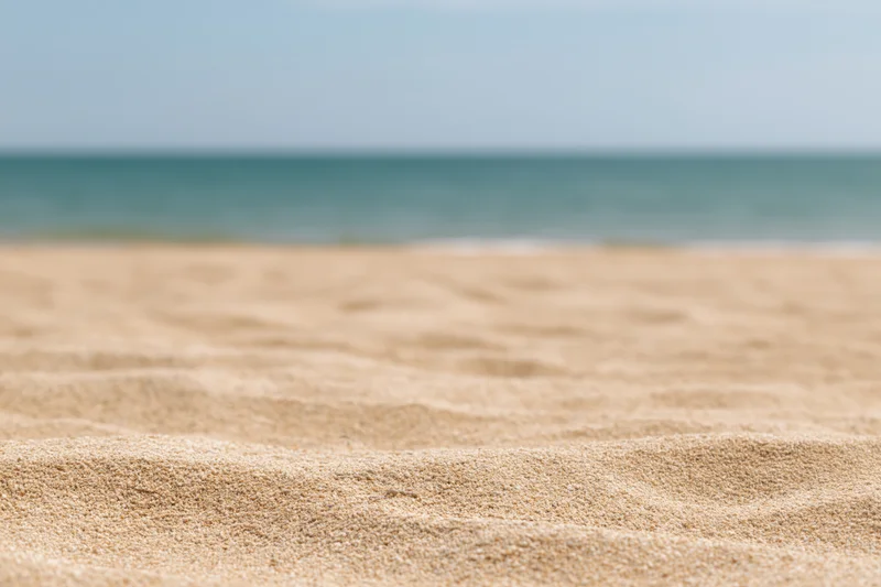 Close-up of textured sand on a beach with ocean in the background