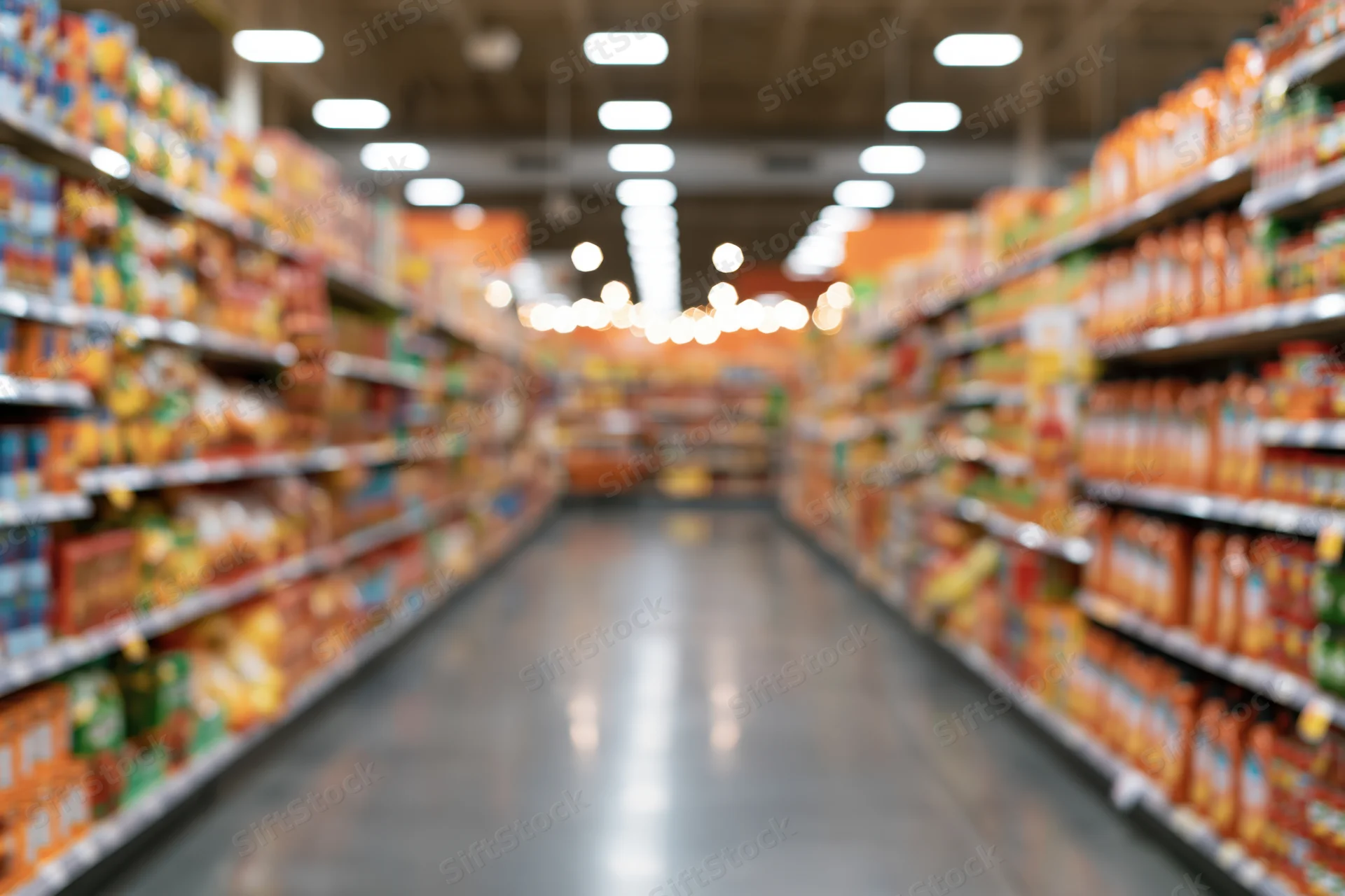 Empty supermarket aisle viewed from low angle with blurred shelves and fluorescent lighting overhead