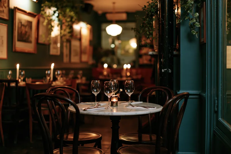 Round marble-top table set with wine glasses and candle in dimly lit upscale bistro interior