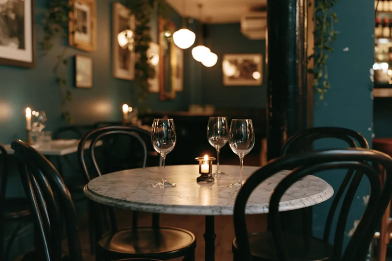 Round marble-top table set with wine glasses and candle in empty upscale bistro interior