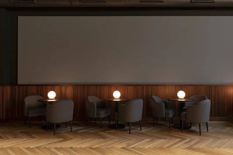 Empty upscale cafe interior with three small round tables each set for two, featuring warm ambient lighting and herringbone wood flooring
