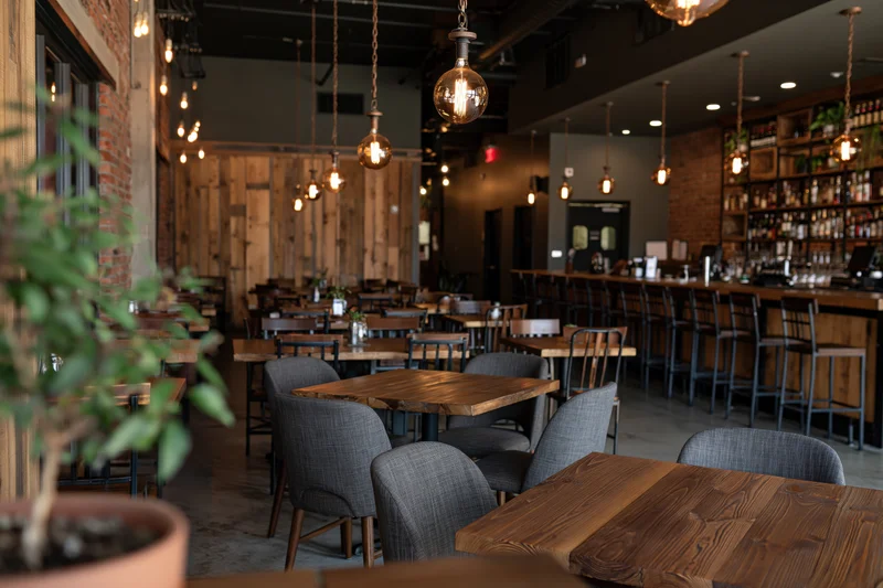 Empty upscale casual restaurant interior with wooden tables and pendant lighting during quiet hours