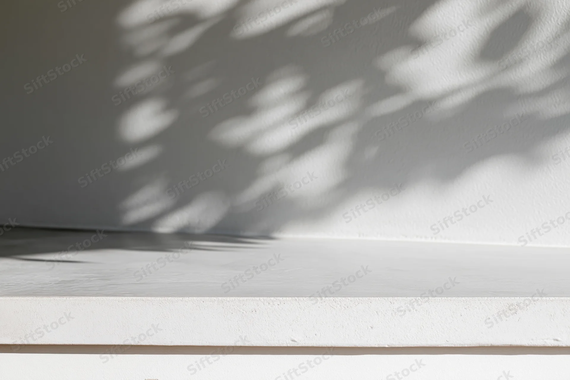 White concrete surface with dappled leaf shadows on adjacent wall corner