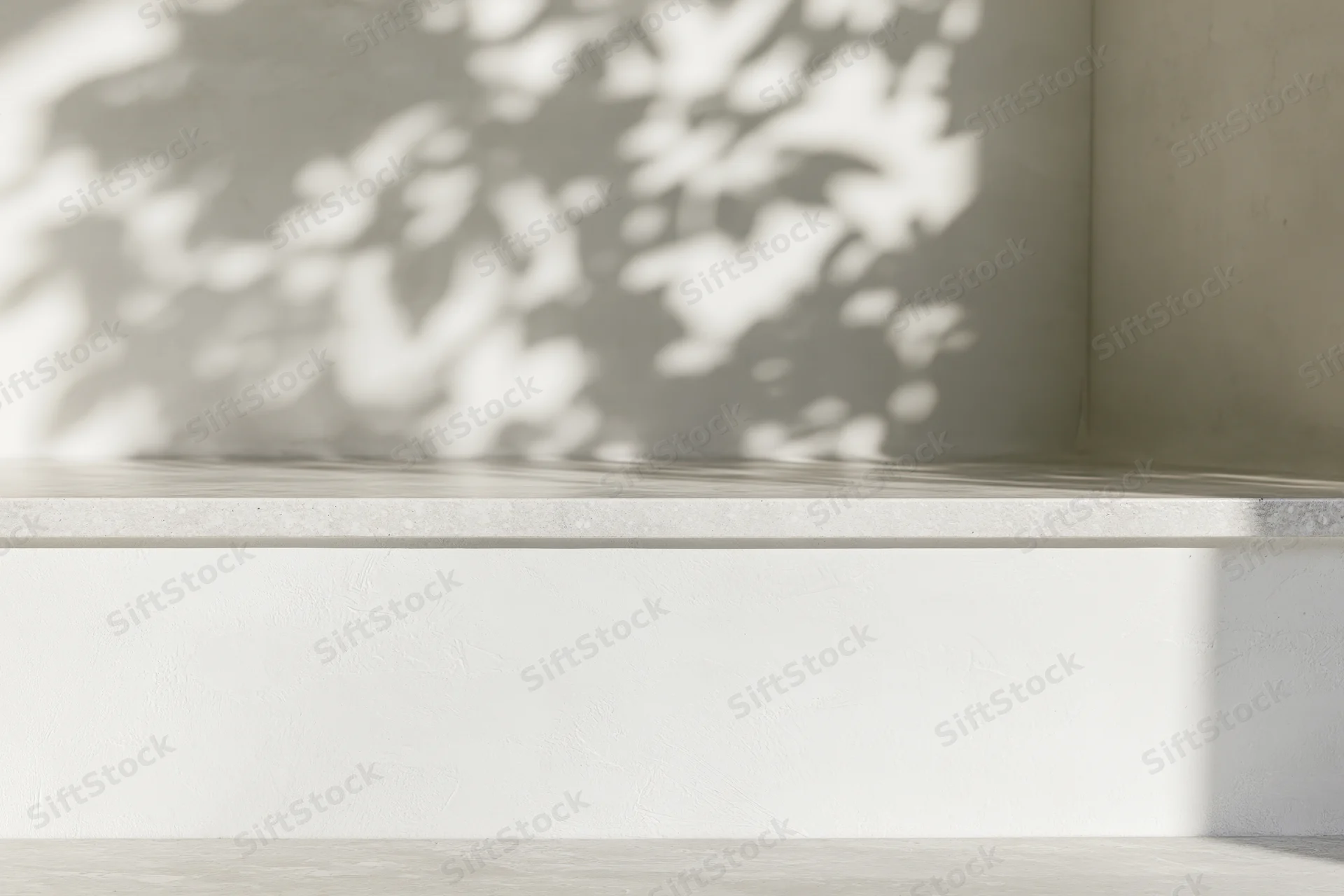 Empty white concrete shelf in a minimalist interior with dappled leaf shadows on the wall