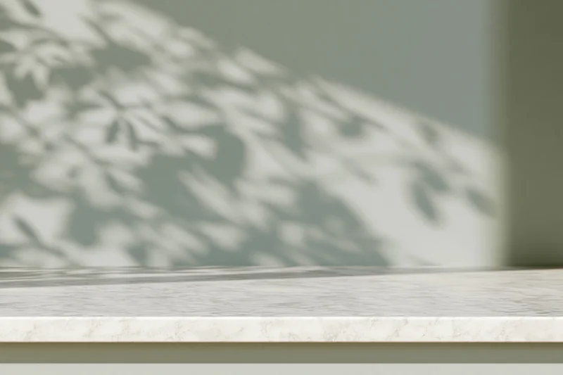 White marble tabletop with dappled leaf shadows from a window in a modern interior