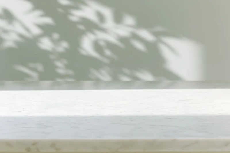 White marble surface with soft leaf shadow projection in interior setting