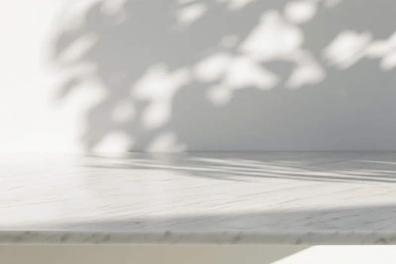 White marble tabletop with dappled sunlight shadows in a minimalist interior