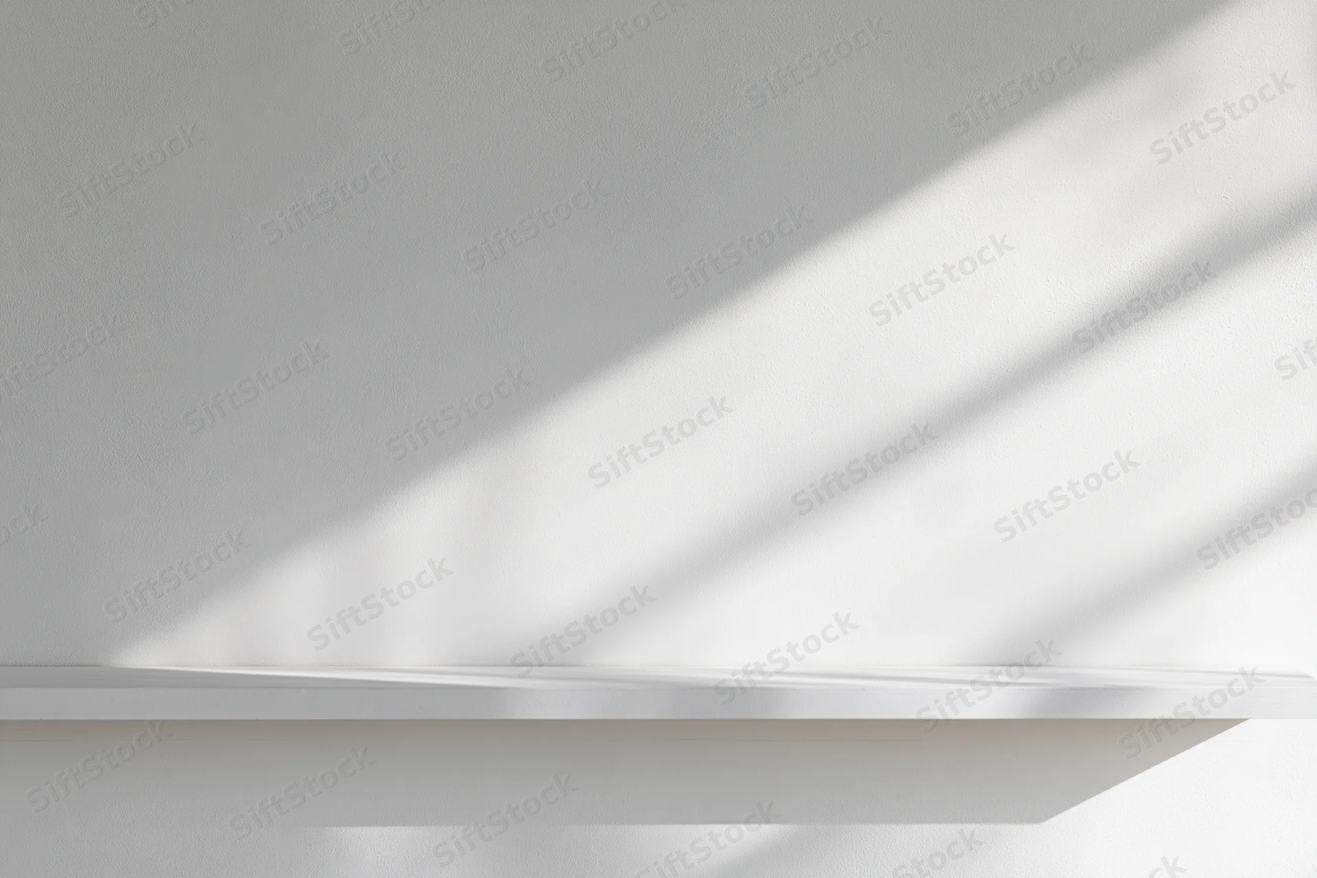 Empty white shelf mounted on a smooth white wall in a minimalist studio space