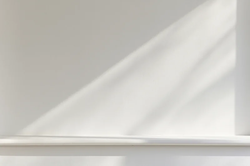 Empty white shelf against a smooth white wall in a minimalist studio space