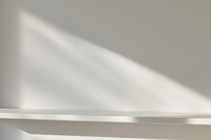 Empty white shelf against a smooth white wall in a minimalist studio space