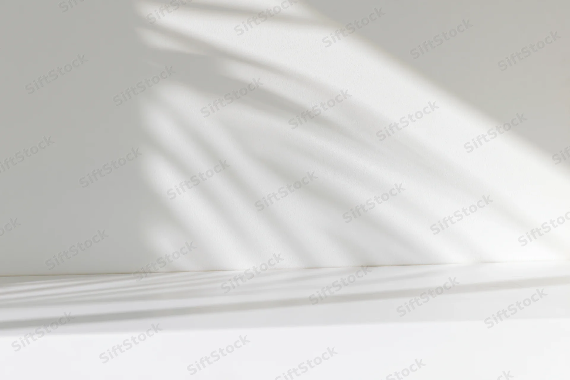 White studio surface and wall with soft light and shadow patterns