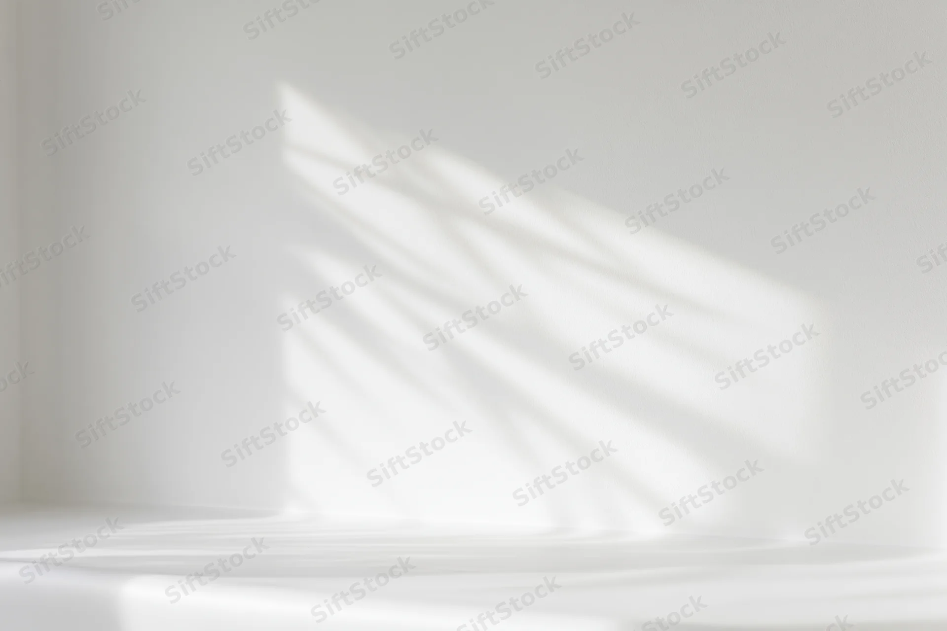 White studio interior with soft light and shadow patterns on wall and floor