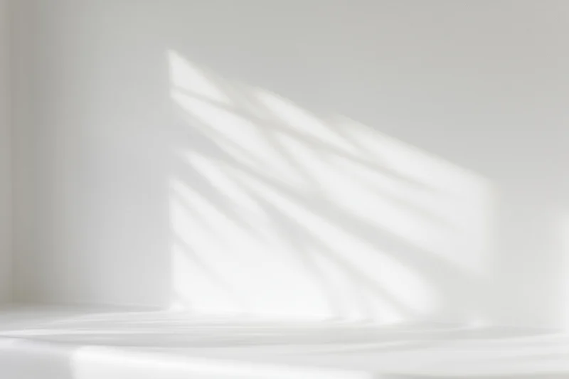 White studio interior with soft light and shadow patterns on wall and floor