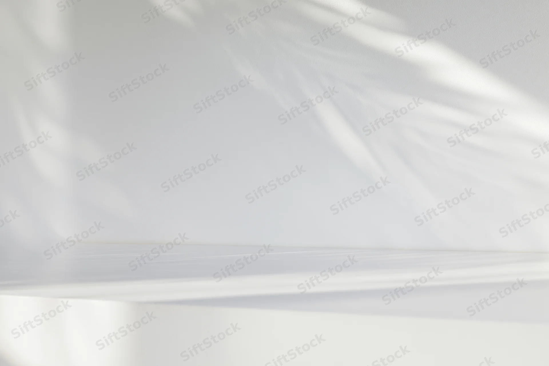White studio surface and wall with soft light and shadows, empty space for display