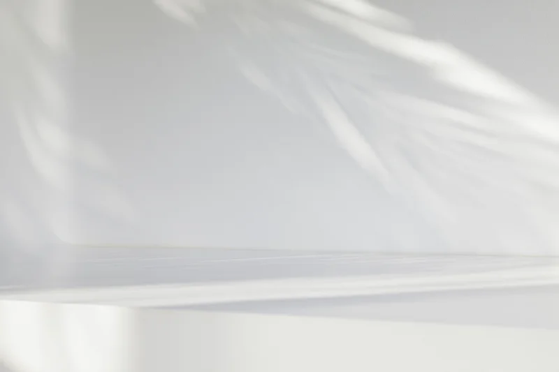 White studio surface and wall with soft light and shadows, empty space for display