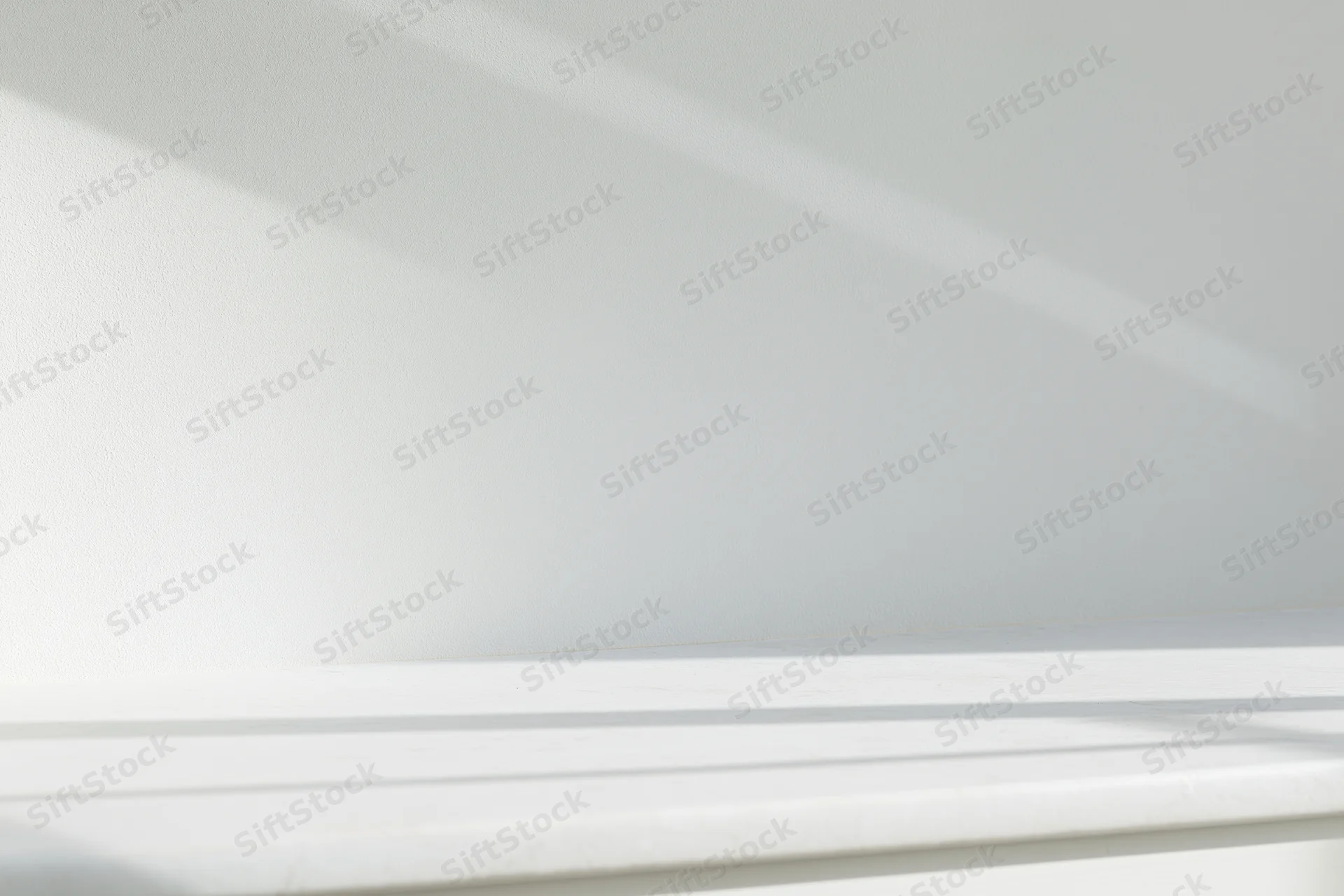 Empty white shelf against a smooth white wall in a minimalist interior