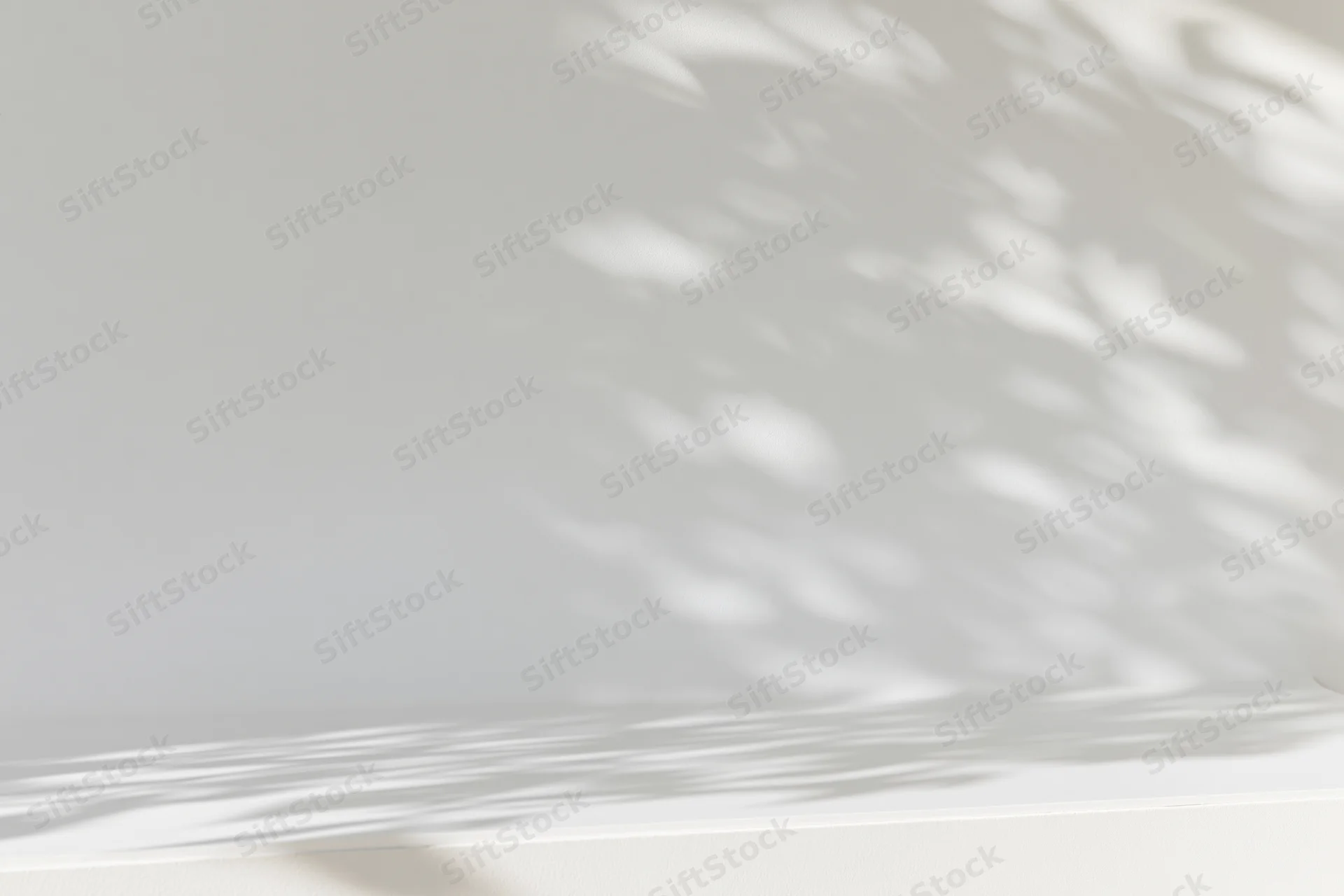 White wall and surface with soft dappled shadows from sunlight filtering through foliage
