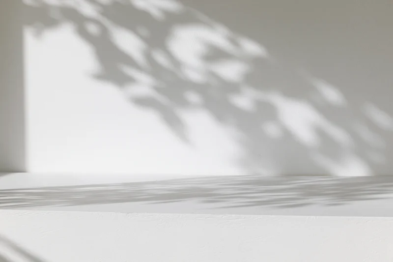 White surface and wall with dappled sunlight shadows in minimalist interior
