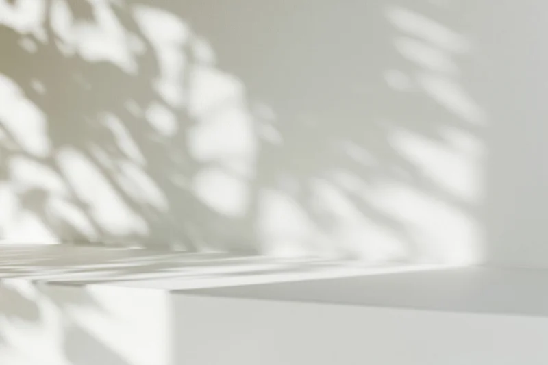 White surface with dappled light shadows on wall in minimalist interior