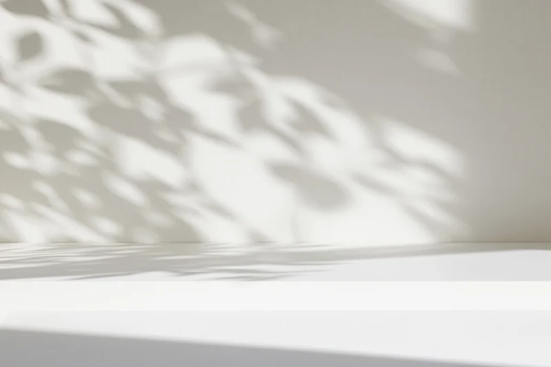 White surface with dappled shadows on a wall in a minimalist interior