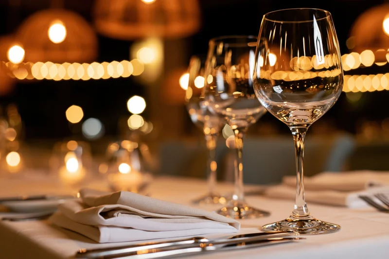 Empty wine glasses and folded linen napkins on a formally set dinner table at night