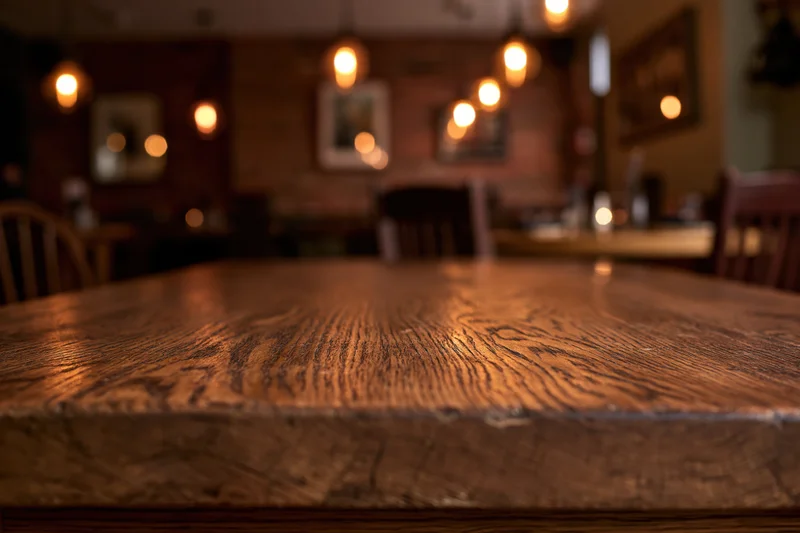 Wooden table surface in focus with blurred restaurant interior behind