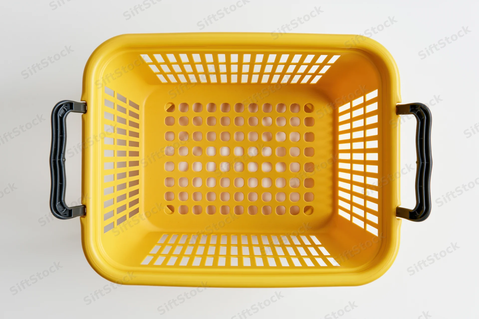 Empty yellow plastic shopping basket with black handles viewed from above on white background
