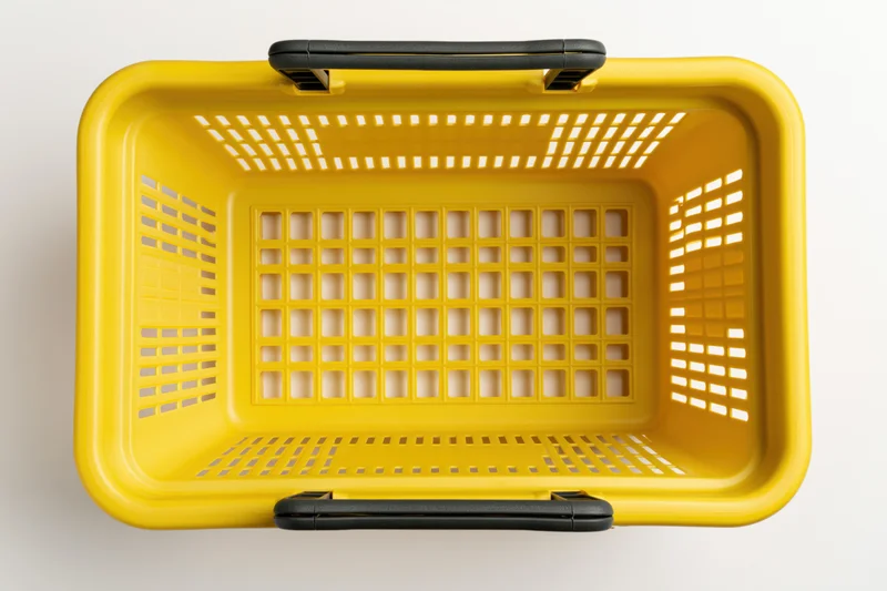 Empty yellow plastic shopping basket viewed from above on white background