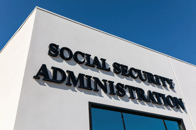 Exterior corner of a government office building with bold black lettering reading social security administration against a blue sky