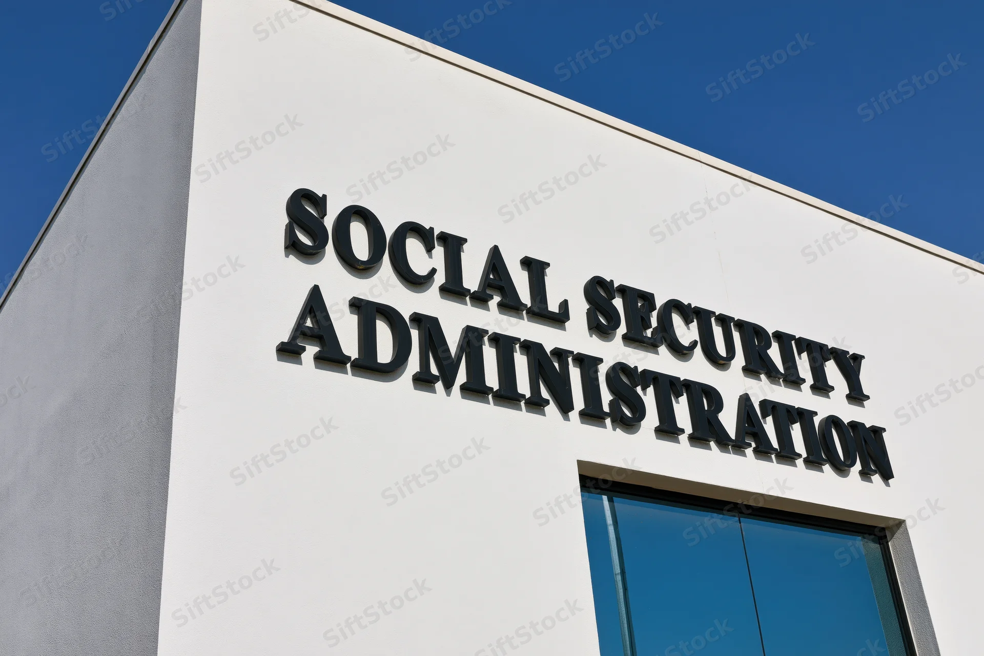 Exterior corner of a government office building with bold black lettering reading social security administration under a clear blue sky
