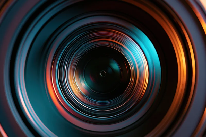 Extreme close-up view into a camera lens showing concentric rings and colorful reflections