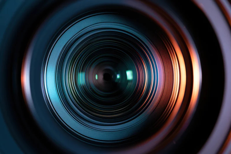 Extreme close-up view into a camera lens showing concentric glass rings and light reflections