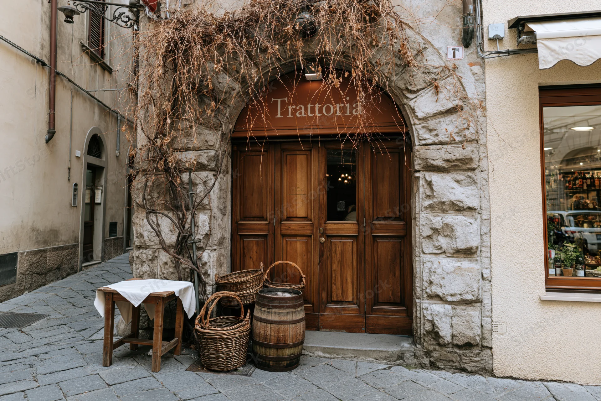 Entrance to a traditional italian trattoria restaurant with wooden door and stone arch on a cobblestone alley