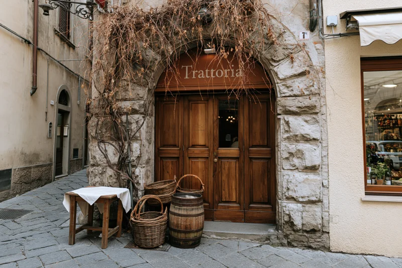 Entrance to a traditional italian trattoria restaurant with wooden door and stone arch on a cobblestone alley