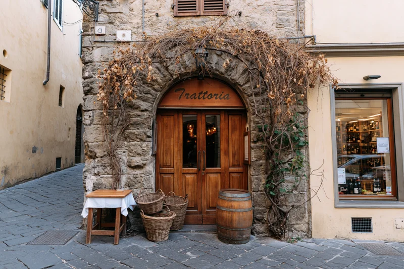 Traditional italian trattoria facade with arched wooden door and stone walls on a cobblestone alley