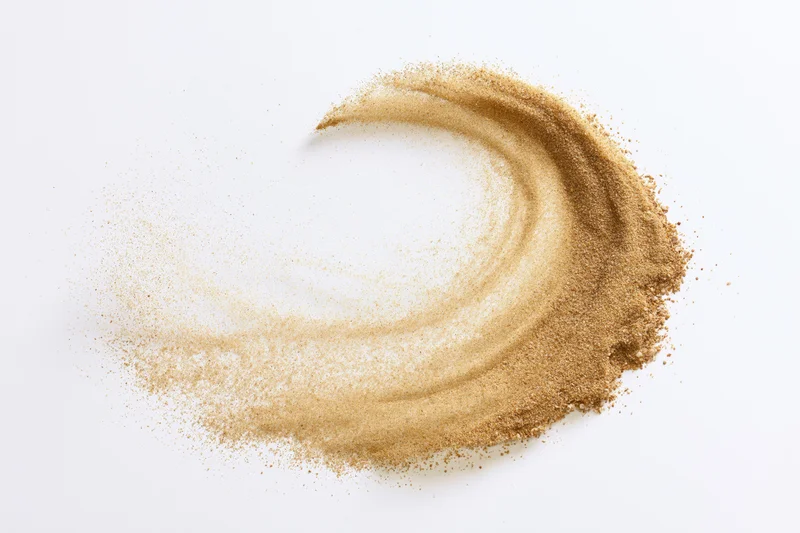 Swirling beach sand frozen in mid-air motion against white background