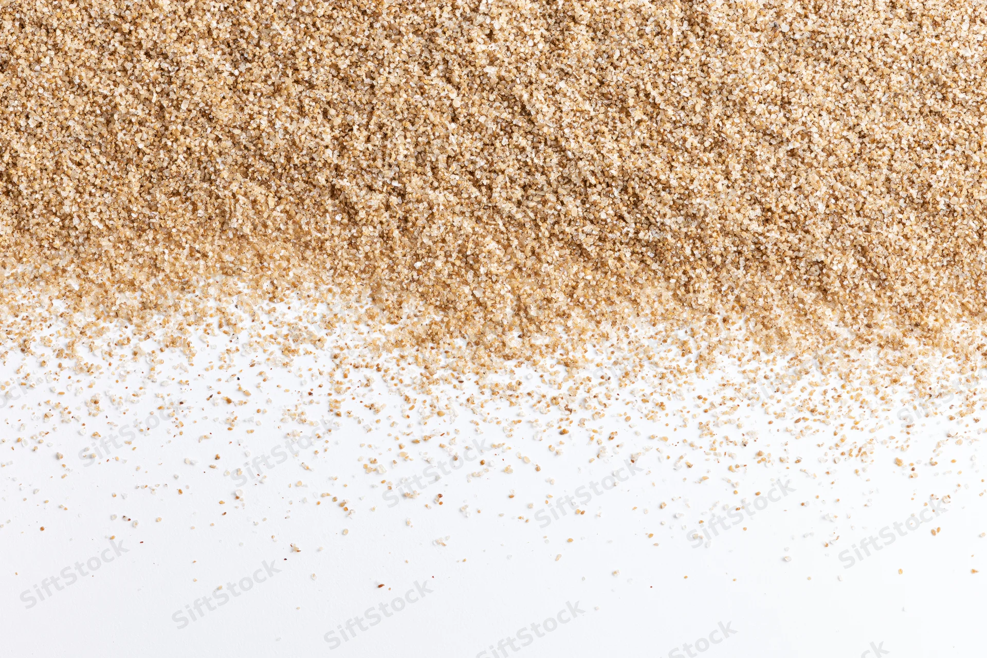 Fine beach sand scattered across a white surface in a flat lay composition