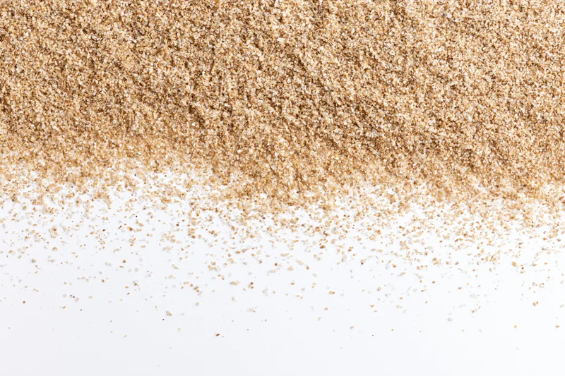 Fine beach sand scattered across a white surface in a flat lay composition
