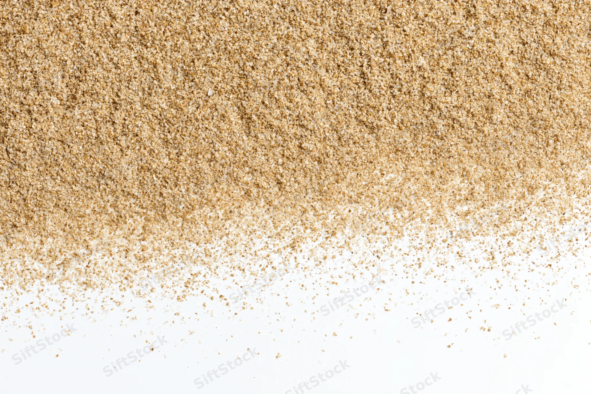Fine beach sand scattered across a white surface forming a textured pile with copyspace below