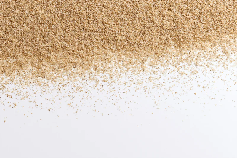 Fine beach sand scattered across a white surface with copyspace below