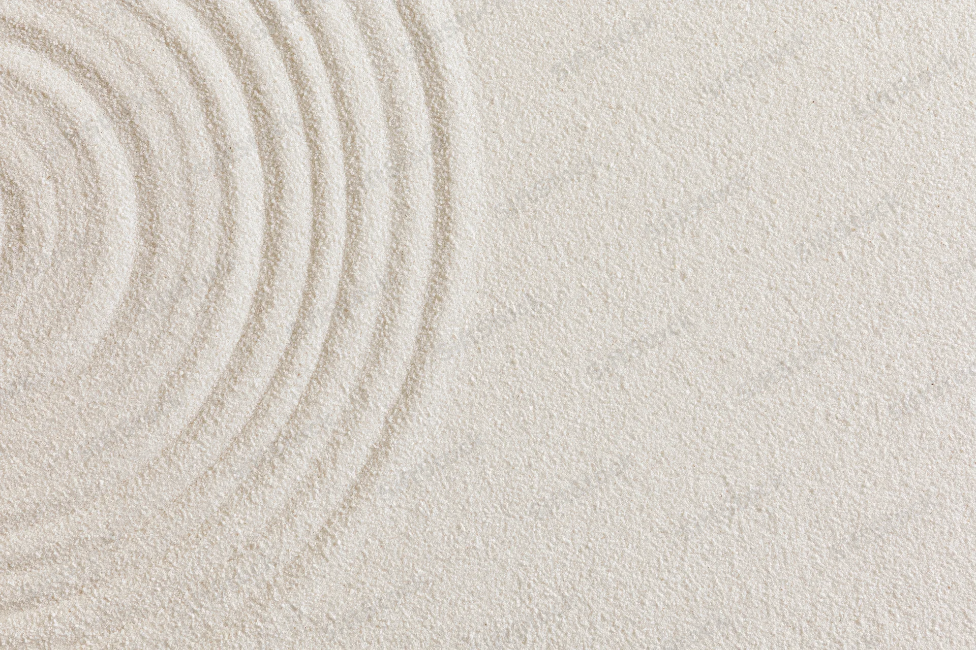 Concentric circles raked into smooth white sand in a zen garden
