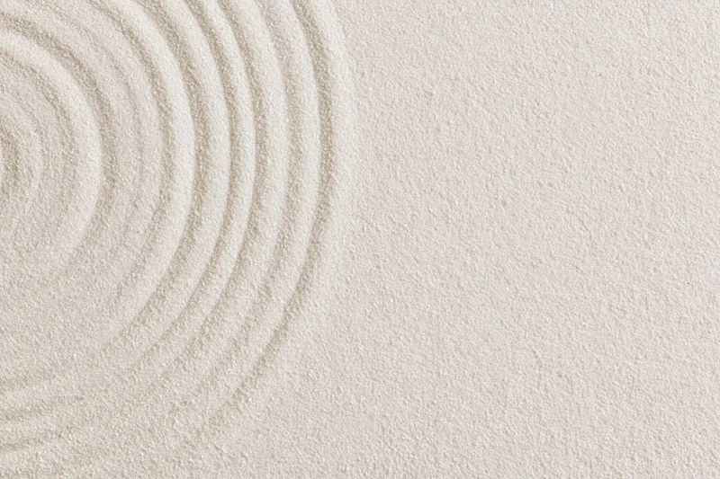 Concentric circles raked into smooth white sand in a zen garden