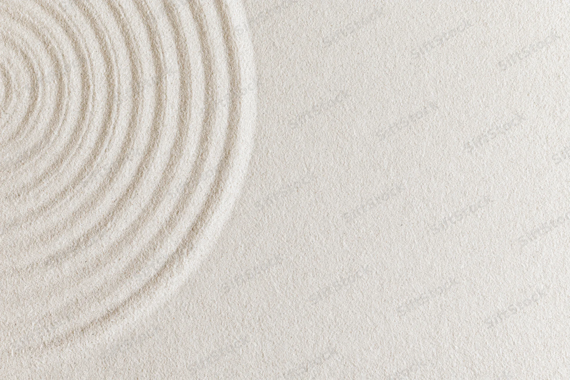 Concentric circles raked into smooth white sand in a zen garden