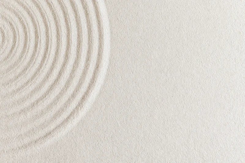 Concentric circles raked into smooth white sand in a zen garden
