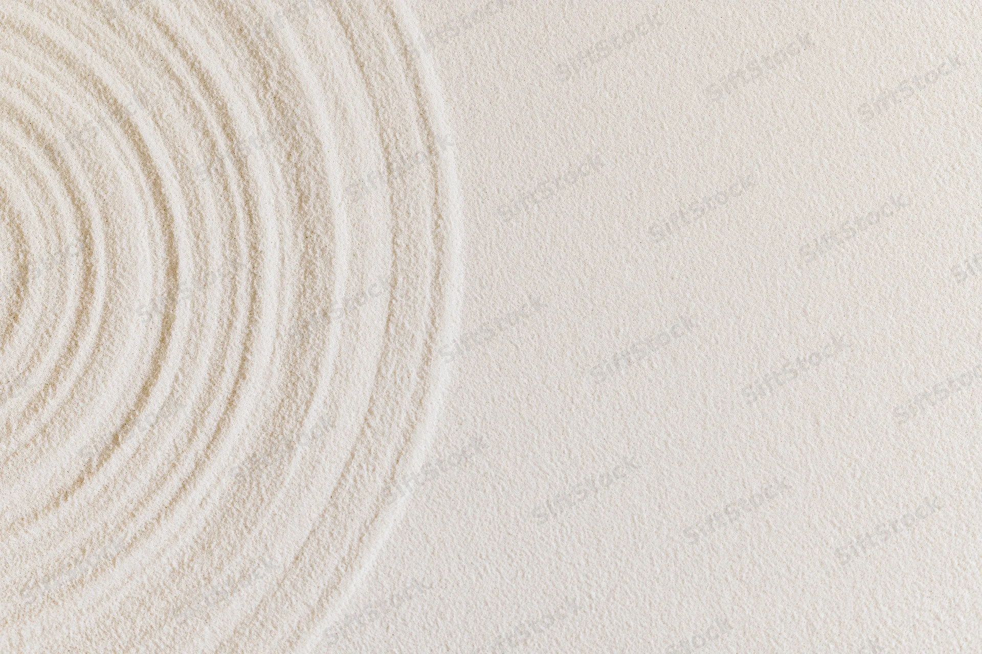 Concentric circles raked into smooth white sand in a zen garden