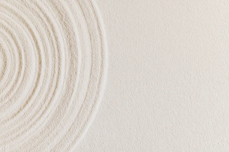 Concentric circles raked into smooth white sand in a zen garden