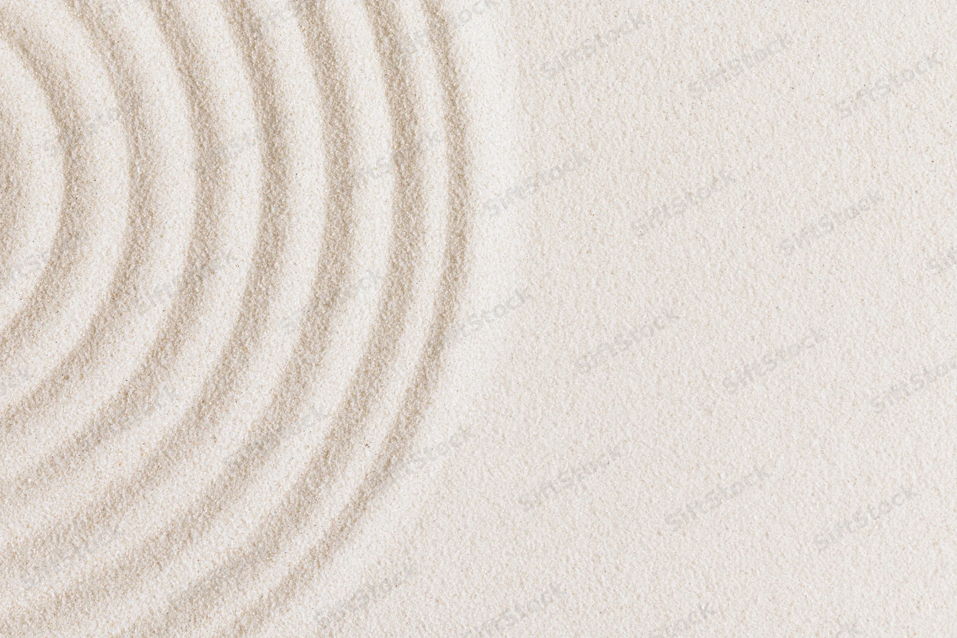 Concentric circles raked into smooth white sand in a zen garden setting