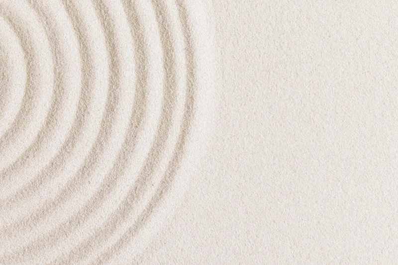 Concentric circles raked into smooth white sand in a zen garden setting
