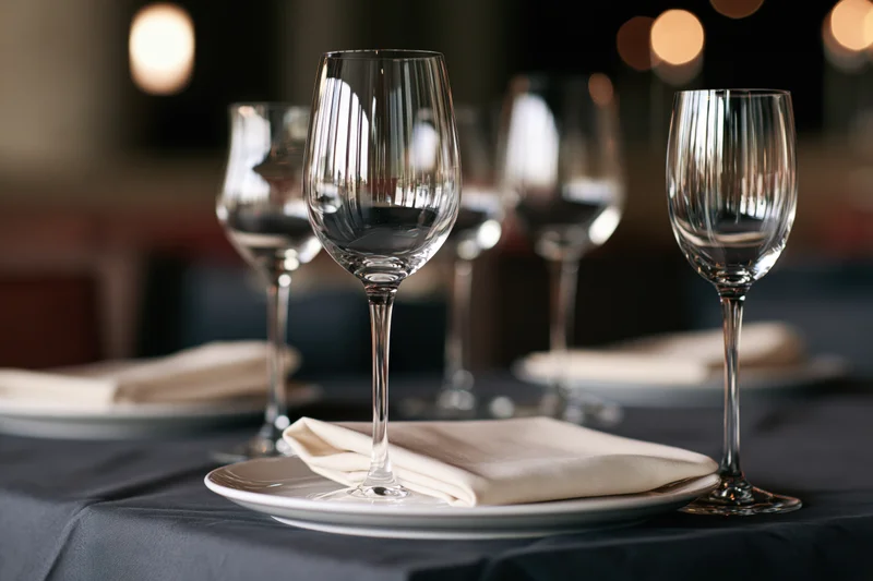 Fine dining table set with empty wine glasses and folded napkins on black cloth