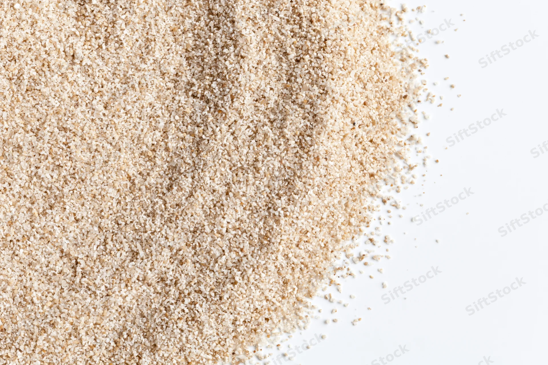 Fine dry beach sand scattered across the upper-left corner of a white surface